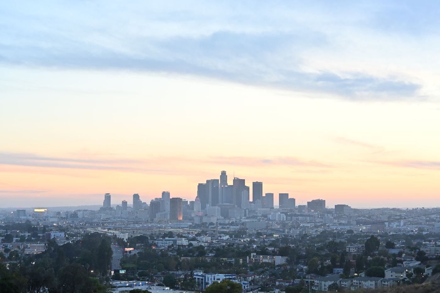 Downtown Los Angeles at last light, the skyline low against a pale sky
