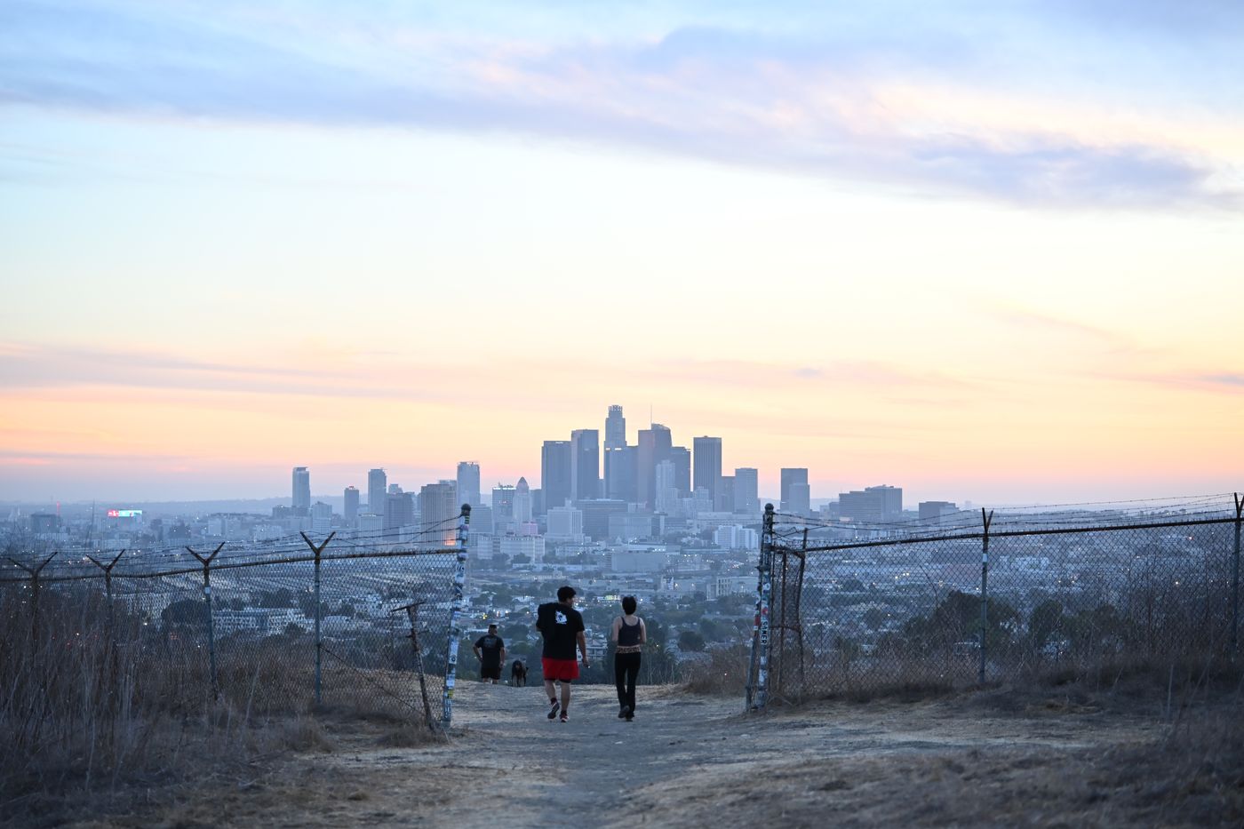 Two figures on a ridge trail above the Los Angeles skyline at dusk