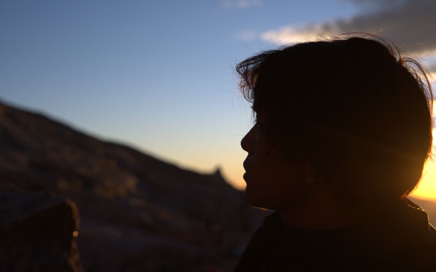 Max in silhouette on a ridge at sunrise, facing the light